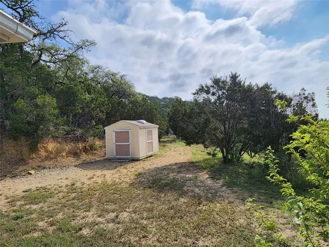 a view of a dry yard with large trees