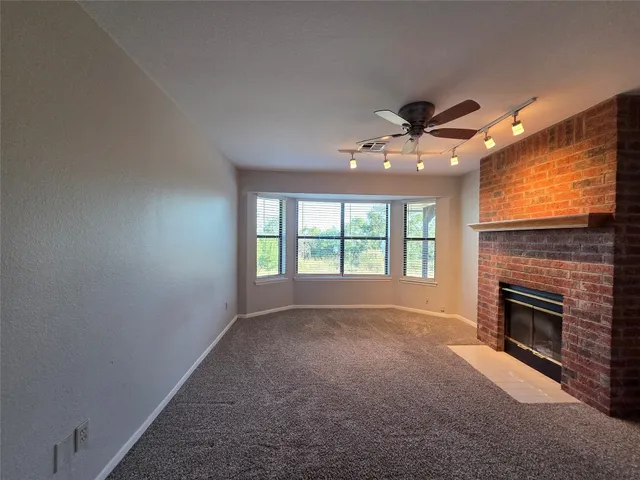 a view of an empty room with a fireplace and a window