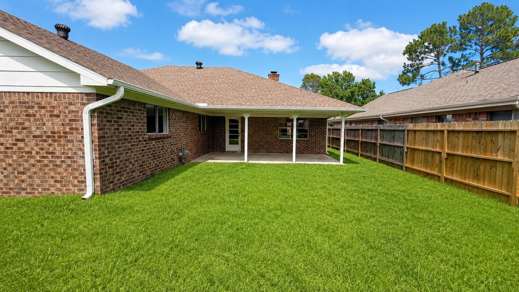 4418 Ponca Street Pasadena, TX 77504 - Photo 23 of 23 Rear yard angle showing the brick elevation, fence line, and patio coverage. (image has been enhance for marketing purposes)