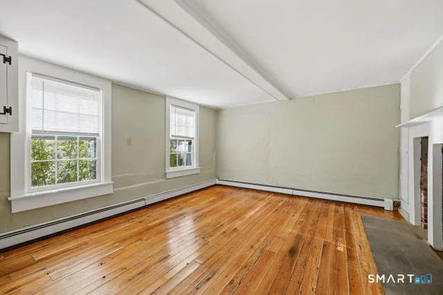 an empty room with wooden floor and fireplace