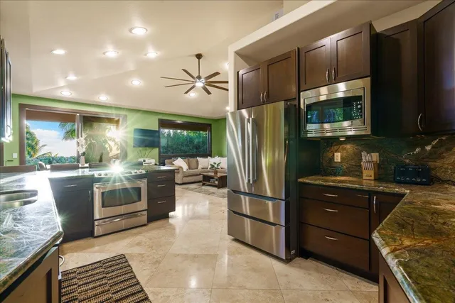 a kitchen with granite countertop a refrigerator and a stove top oven