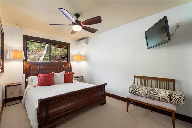 a bedroom with a bed a flat screen tv and a window