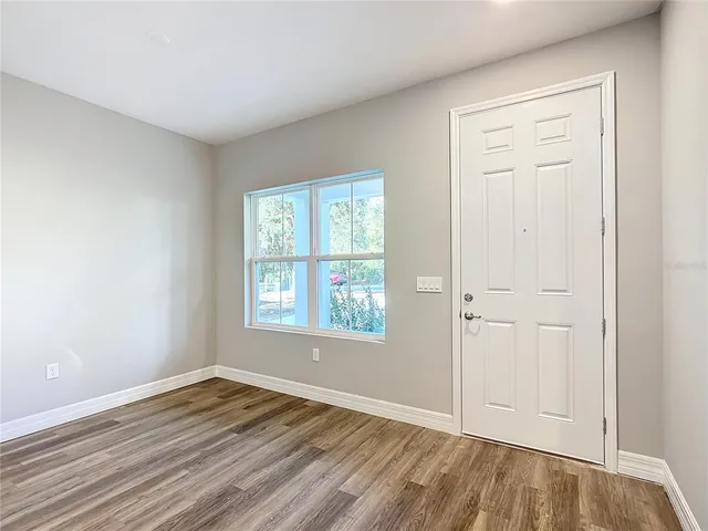 an empty room with wooden floor closet and windows