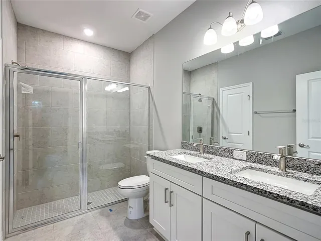a bathroom with a granite countertop sink a toilet and a mirror