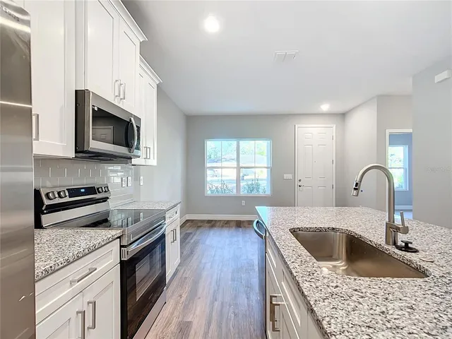 a kitchen with granite countertop a sink wooden floor and stainless steel appliances