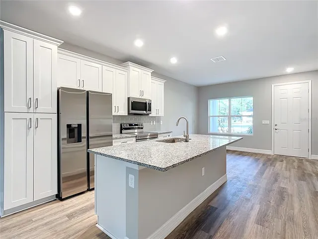 a kitchen with kitchen island granite countertop appliances cabinets a sink and a counter space