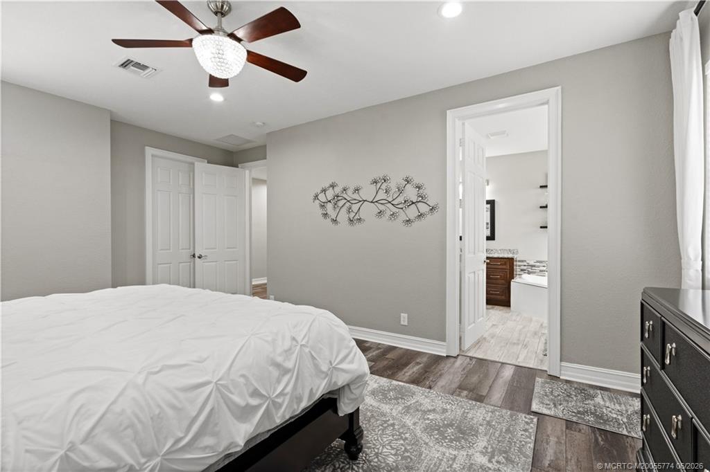 1268 Southeast Kirk Street Stuart, FL 34997 - Photo 34 of 63 a bedroom with a large bed and a chandelier