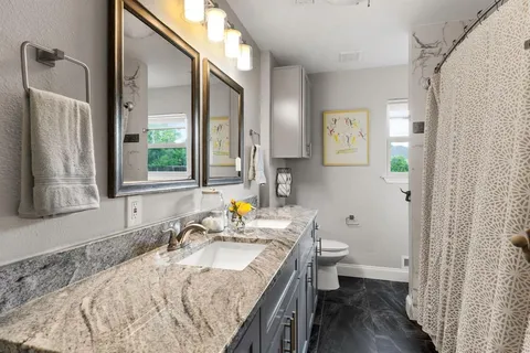 a bathroom with a granite countertop sink a toilet and a mirror