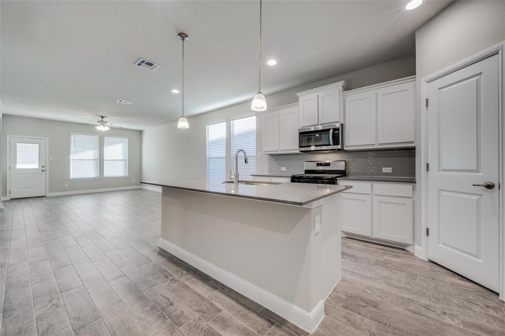 254 Lunayena Road Rhome, TX 76078 - Photo 3 of 8 a kitchen with granite countertop a stove a sink and a refrigerator