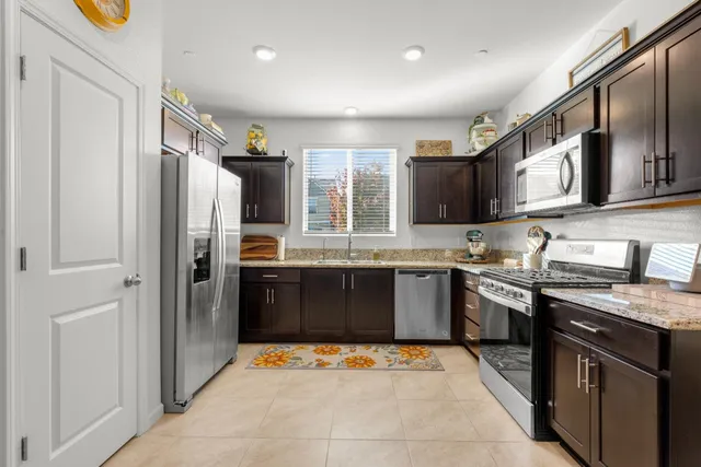 a large kitchen with stainless steel appliances granite countertop a refrigerator and a sink