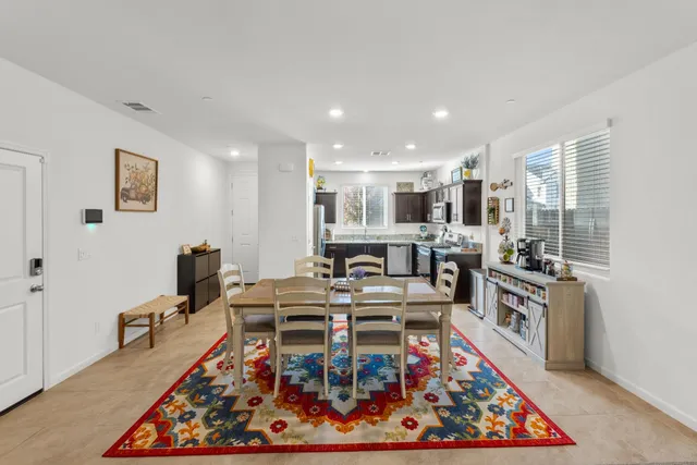 a living room with stainless steel appliances furniture wooden floor and a kitchen view
