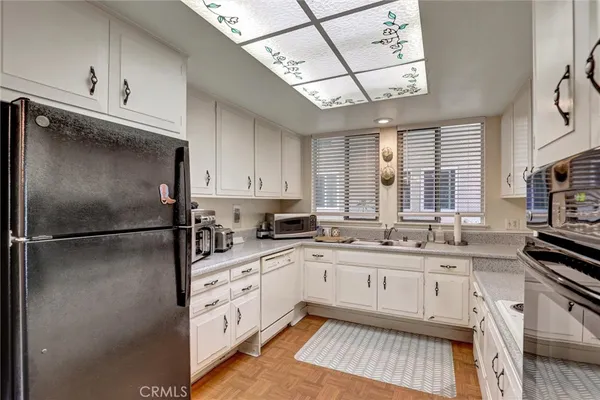 a kitchen with a sink appliances cabinets and a counter space