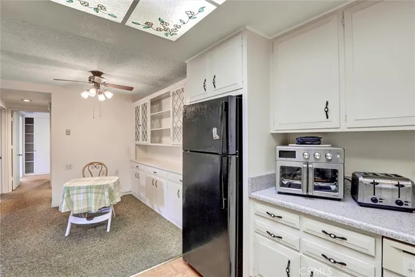 a kitchen with stainless steel appliances granite countertop a refrigerator a stove a sink dishwasher and white cabinets with wooden floor