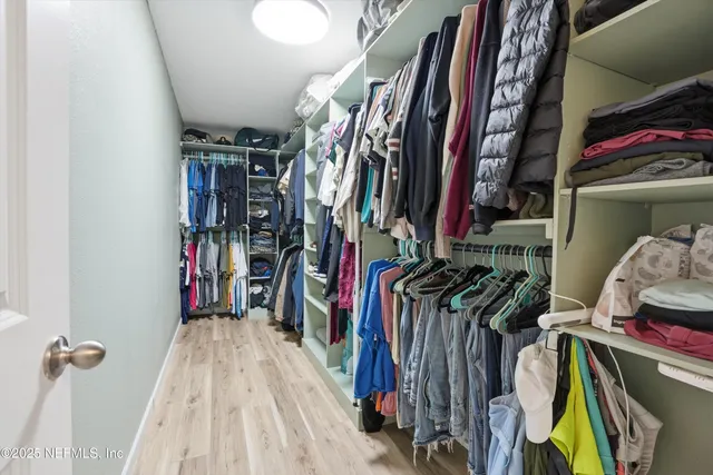 a view of walk in closet with clothes and shoes