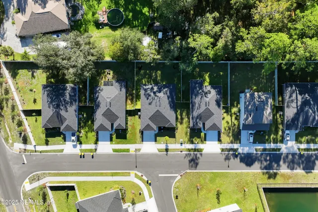 an aerial view of residential houses with outdoor space and trees