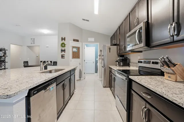 a kitchen with stainless steel appliances granite countertop a sink a stove and a refrigerator