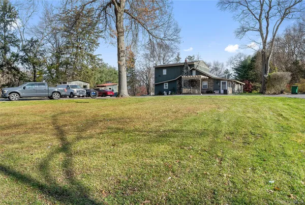 a view of a house with a big yard and large trees
