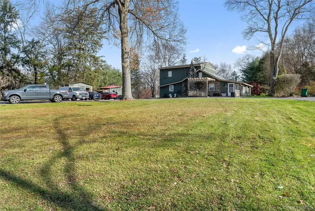 a view of a house with a big yard and large trees