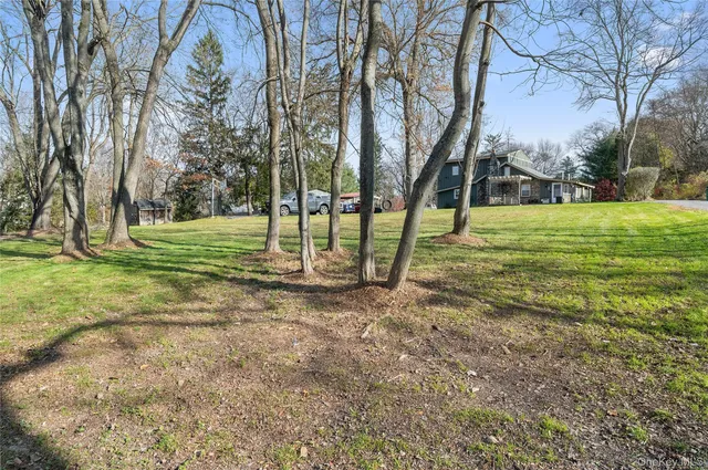 a view of a house with a big yard and large trees