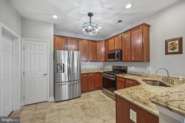 a kitchen with granite countertop stainless steel appliances a sink stove and refrigerator