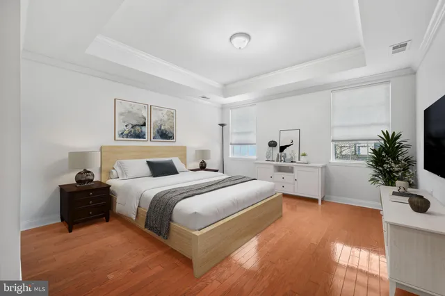 a spacious bedroom with a bed a couch and potted plant on the dresser