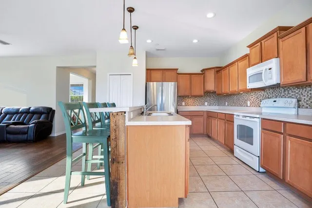 a kitchen with stainless steel appliances granite countertop a stove a sink a oven a dining table and chairs