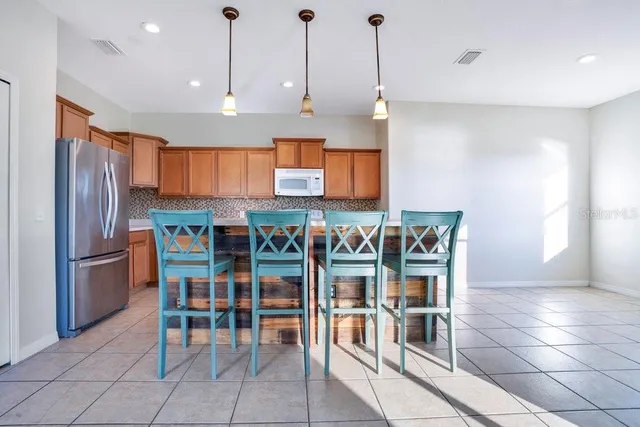 a kitchen with stainless steel appliances kitchen island granite countertop a refrigerator a stove a sink with a dining table and chairs