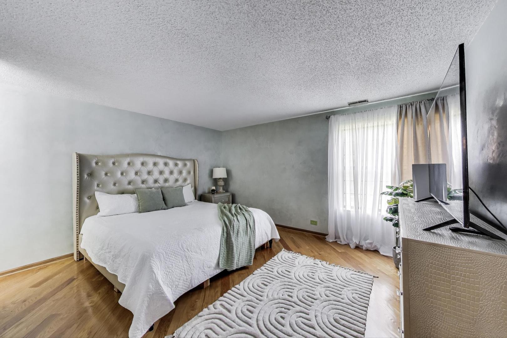 738 Hapsfield Lane, Unit 7A2 Buffalo Grove, IL 60089 - Photo 16 of 29 a bedroom with a bed a large window and wooden floor