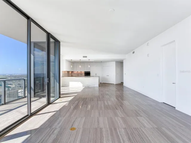 a view of an empty room with wooden floor and iron stairs