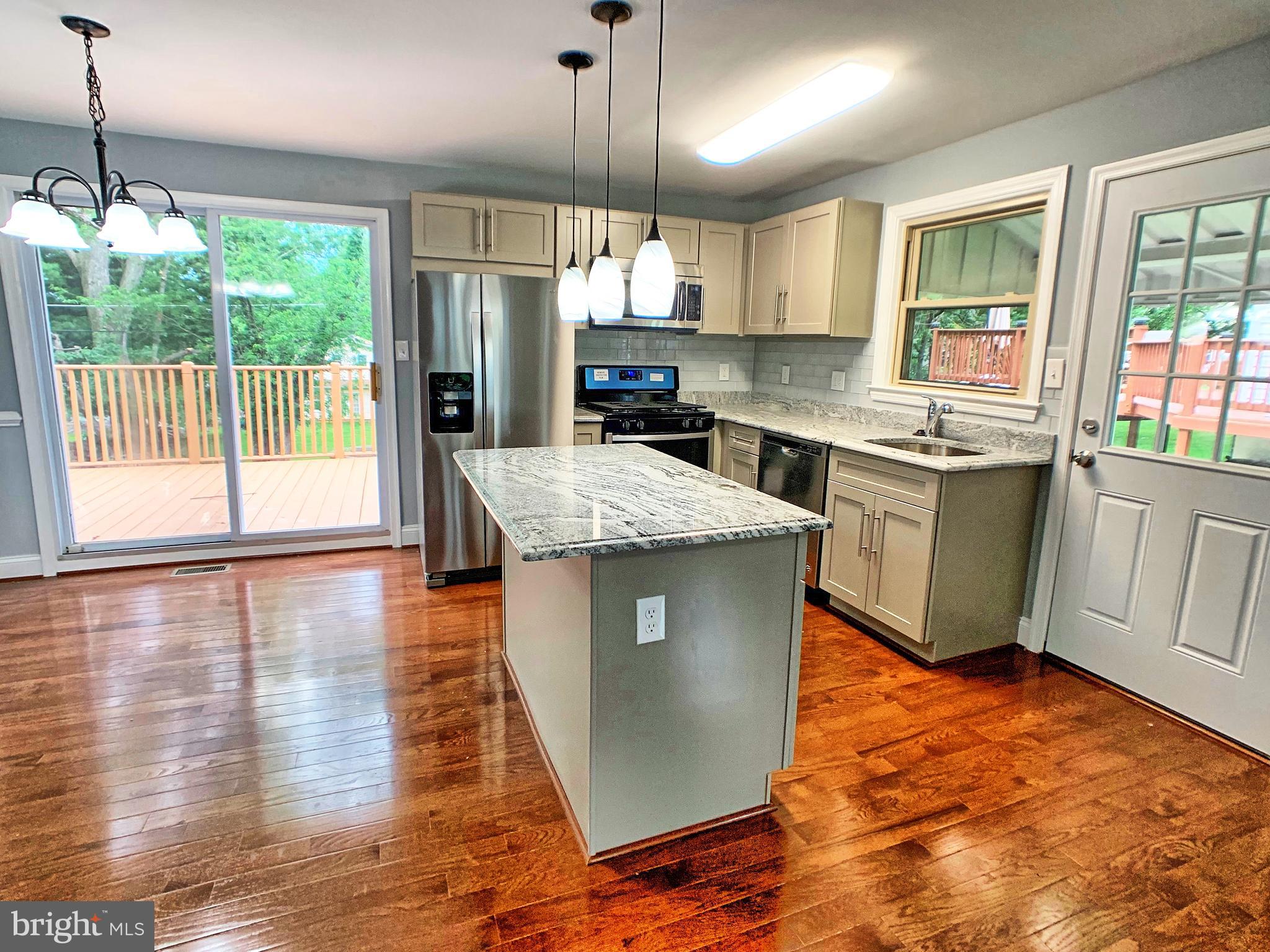 3607 Telmar Road Baltimore, MD 21207 - Photo 5 of 19 a kitchen with stainless steel appliances granite countertop a stove top oven a sink dishwasher a refrigerator and a dining table with wooden floor