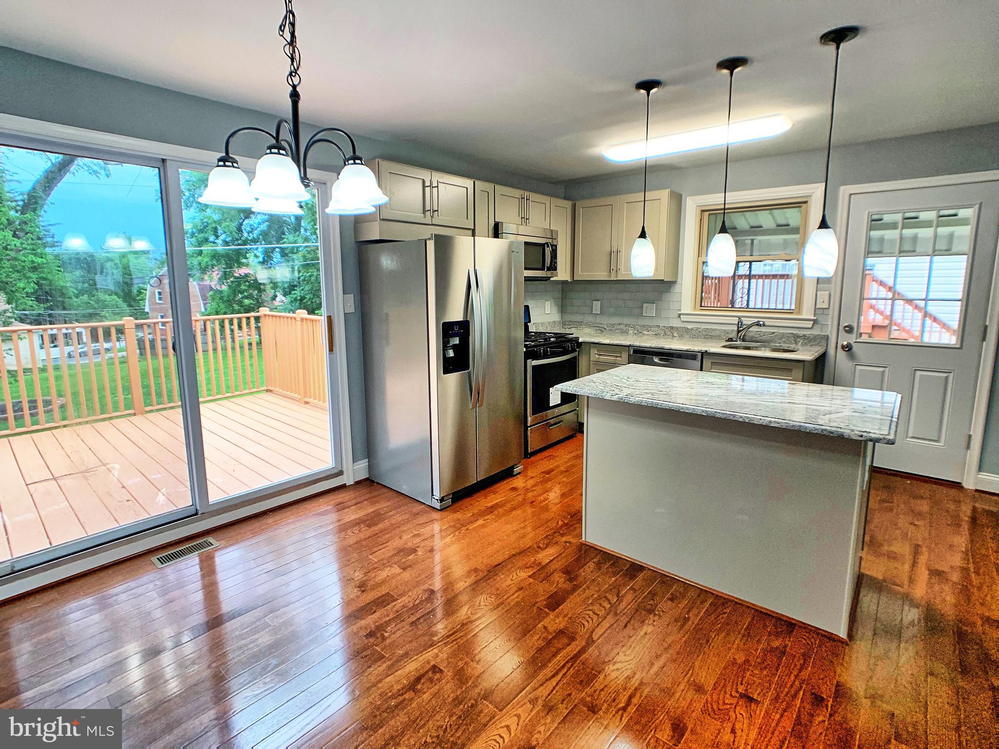 3607 Telmar Road Baltimore, MD 21207 - Photo 6 of 19 a kitchen with stainless steel appliances granite countertop a refrigerator a sink dishwasher a stove and white countertops with wooden floor