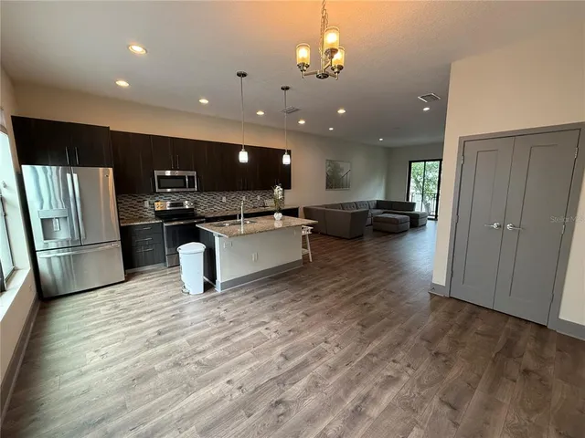 a living room with stainless steel appliances furniture or kitchen view and a refrigerator
