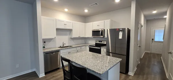 a kitchen with stainless steel appliances granite countertop a sink stove refrigerator and cabinets