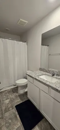 a bathroom with a granite countertop sink and a toilet