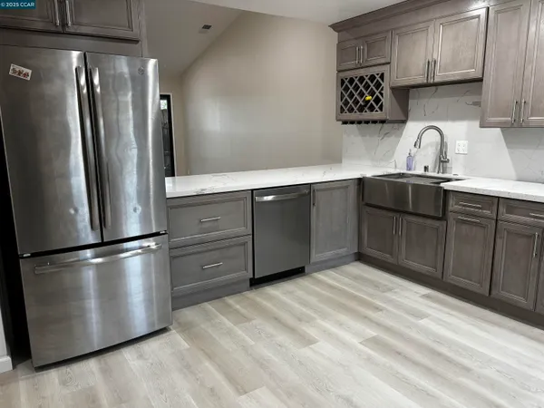 a kitchen with stainless steel appliances granite countertop a refrigerator a sink and wooden cabinets