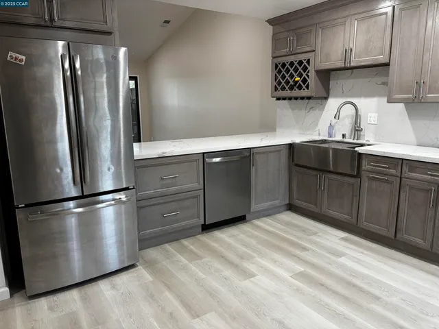 a kitchen with stainless steel appliances granite countertop a refrigerator a sink and wooden cabinets