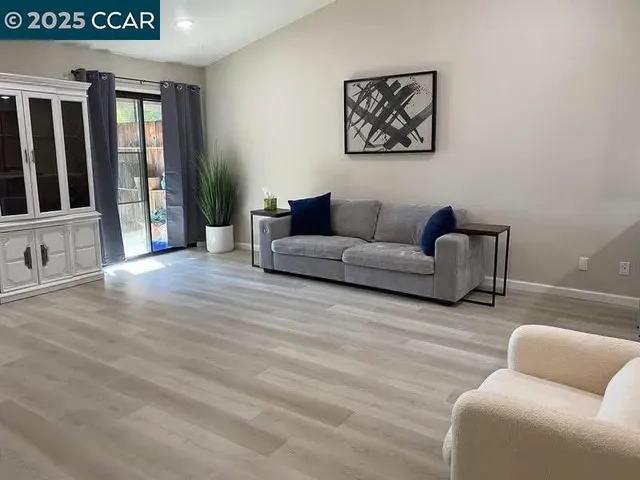 a living room with furniture a flat screen tv and kitchen view