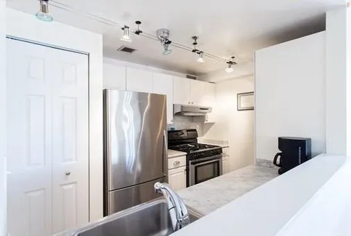 a kitchen with stainless steel appliances a refrigerator and a stove top oven