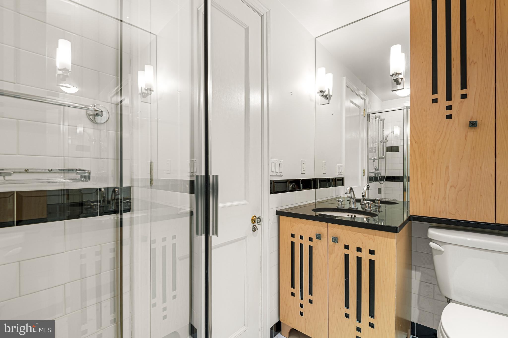 3908 North Charles Street, Unit 501 Baltimore, MD 21218 - Photo 40 of 54 a bathroom with a granite countertop sink a toilet a mirror and shower