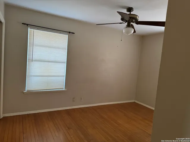a view of a small space with wooden floor a ceiling fan and a window