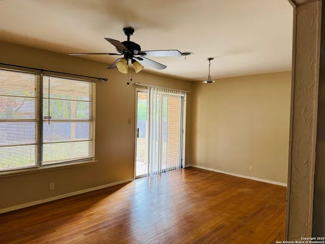 a view of empty room with wooden floor and fan