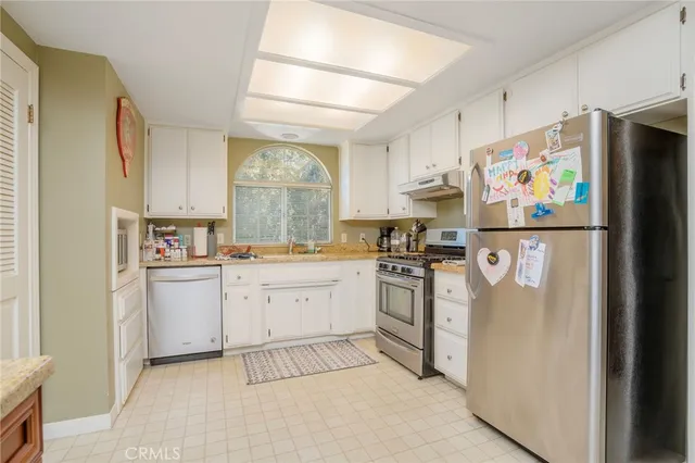 a large kitchen with stainless steel appliances lots of counter space sink and a dishwasher