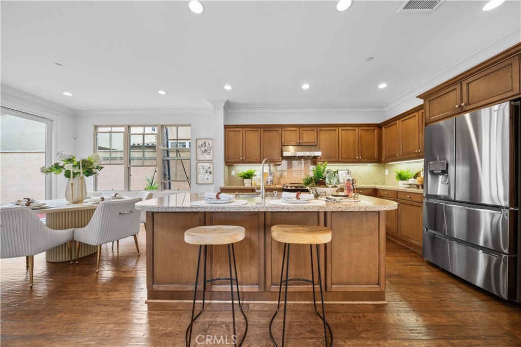 33 Jonquil Irvine, CA 92618 - Photo 12 of 48 a kitchen with stainless steel appliances granite countertop a stove a sink a refrigerator and a dining table with wooden floor