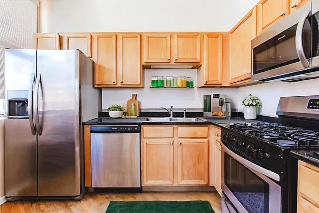 a kitchen with stainless steel appliances granite countertop a refrigerator sink and stove