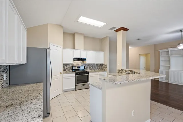 a kitchen with stainless steel appliances granite countertop a sink a stove a refrigerator and island