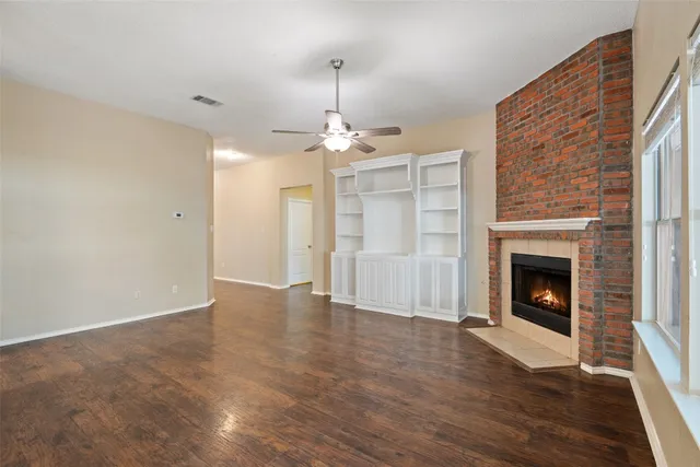 a view of a livingroom with wooden floor a fireplace and window