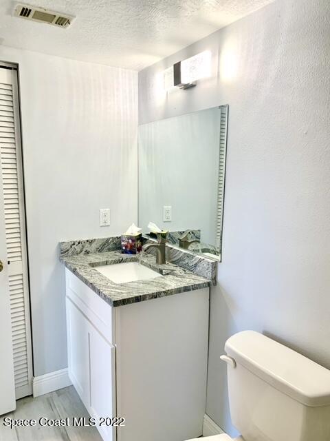 584 North Wickham Road, Unit 82 Melbourne, FL 32935 - Photo 11 of 43 a bathroom with a granite countertop sink a toilet and a mirror