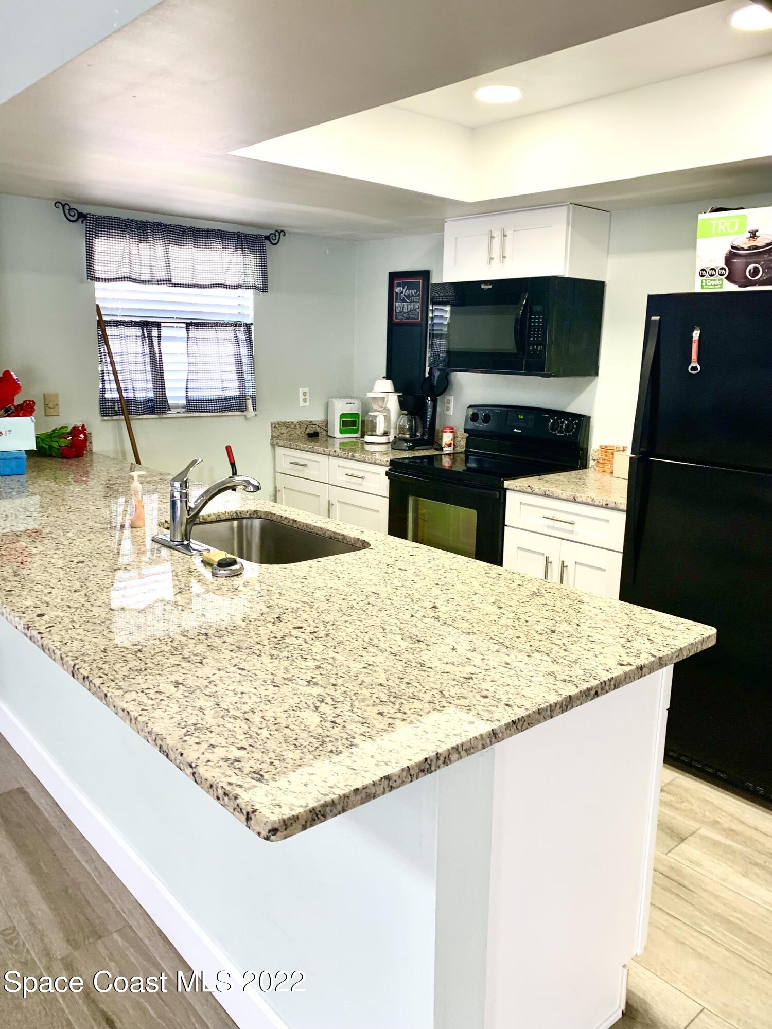 584 North Wickham Road, Unit 82 Melbourne, FL 32935 - Photo 26 of 43 a kitchen with kitchen island a sink stainless steel appliances and counter space