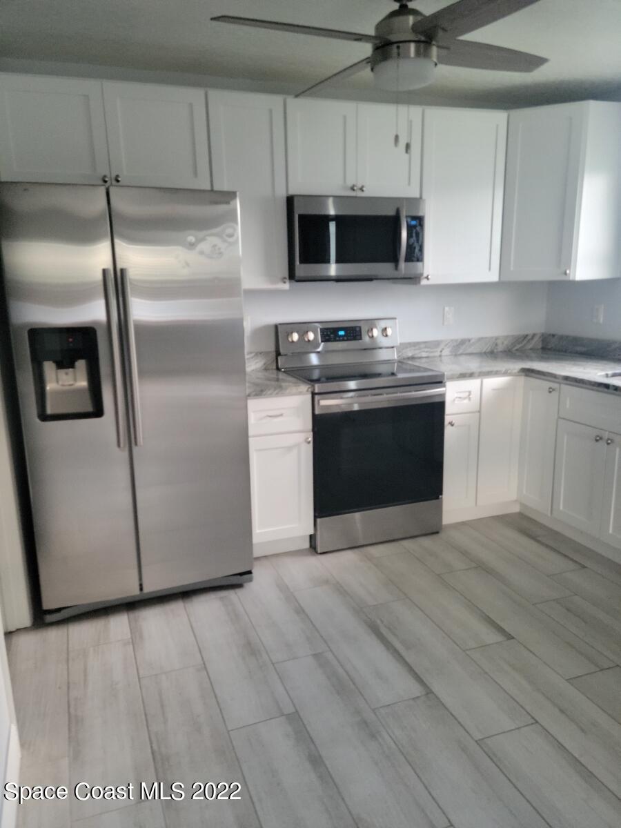 584 North Wickham Road, Unit 82 Melbourne, FL 32935 - Photo 6 of 43 a kitchen with stainless steel appliances a stove a microwave and a sink