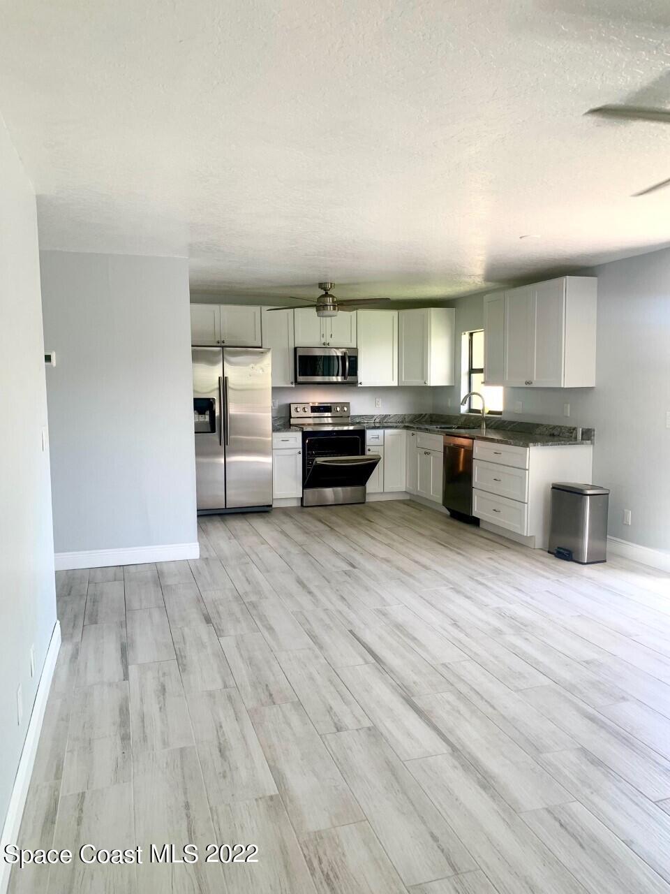 584 North Wickham Road, Unit 82 Melbourne, FL 32935 - Photo 7 of 43 a large kitchen with cabinets wooden floor and stainless steel appliances